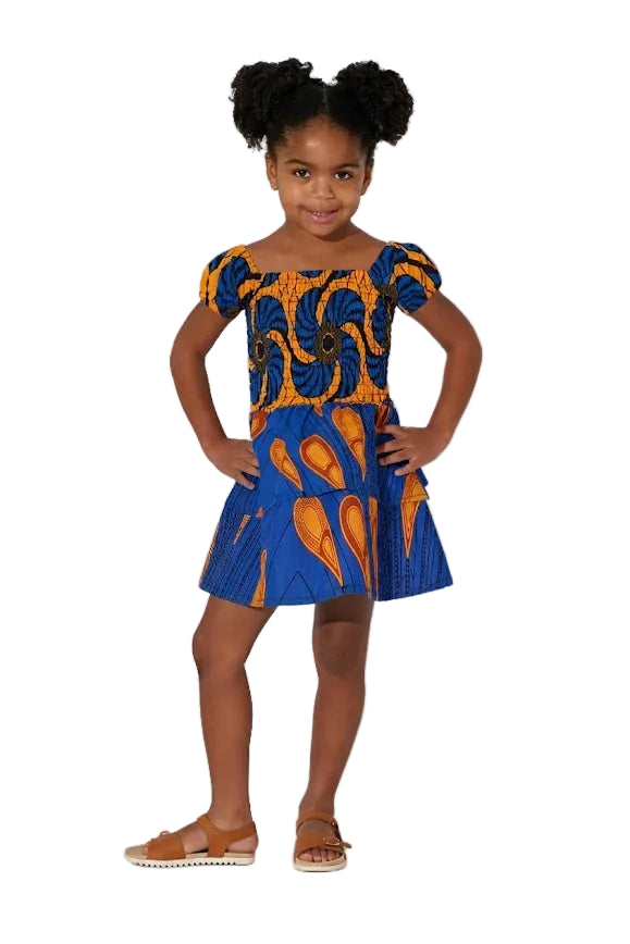 Young girl wearing a blue and orange patterned dress on a white background